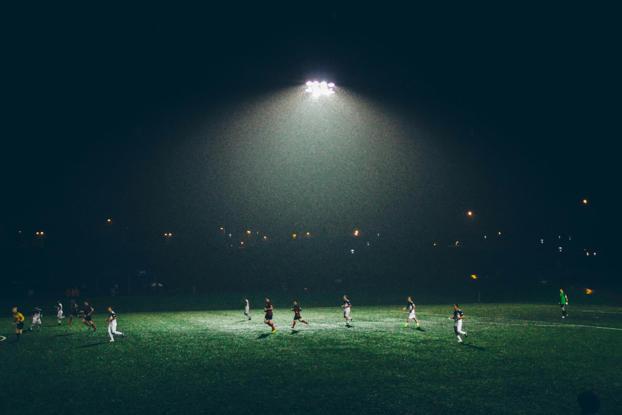 Meci de fotbal noaptea, sub conul de lumină al unei singure nocturne