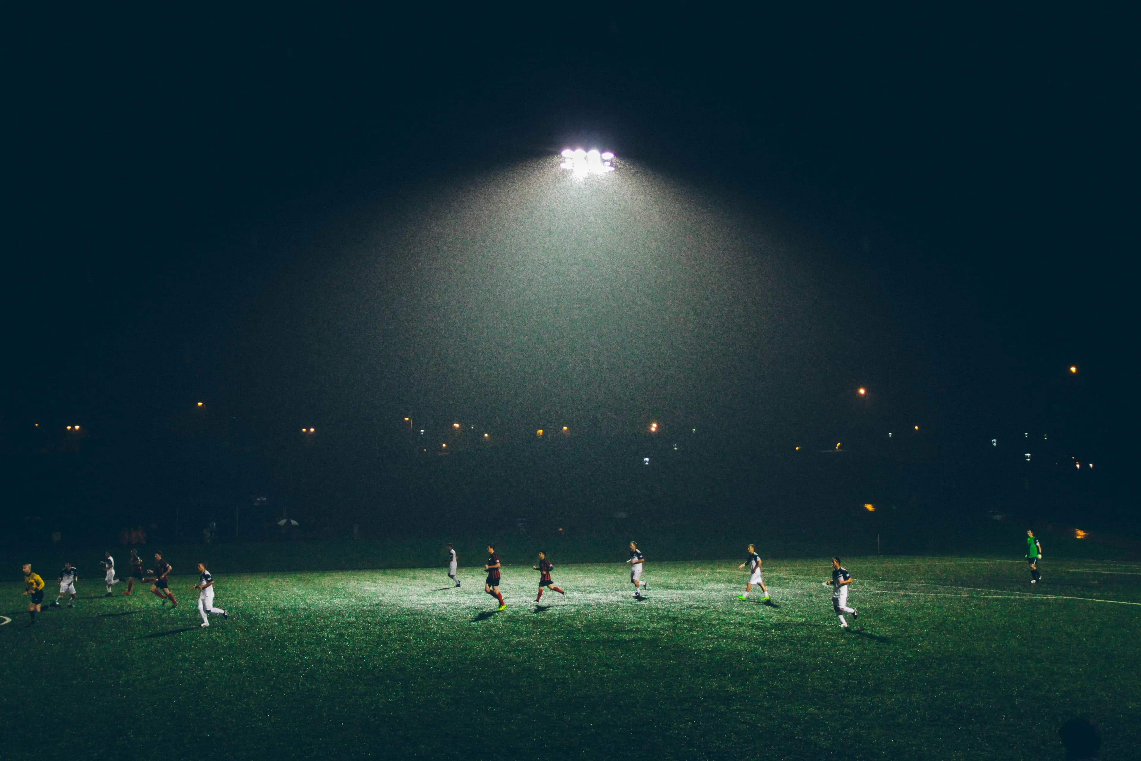 Meci de fotbal noaptea, sub conul de lumină al unei singure nocturne